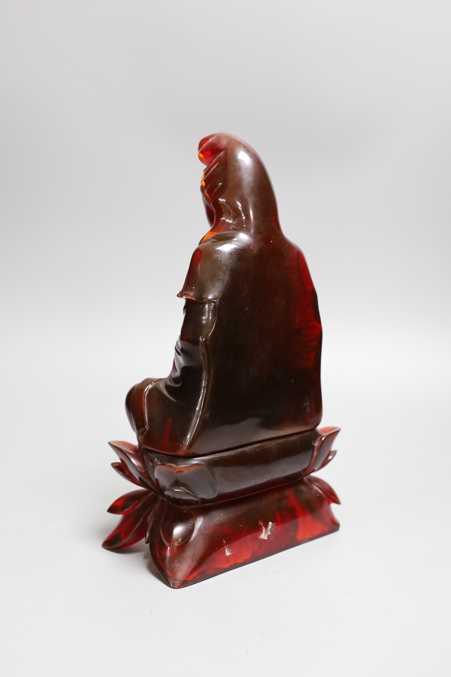 A Chinese ‘cherry amber’ phenolic seated figure of Guanyin, 29cms high
